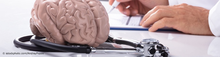 Auf docinsider registrierter Neurologe sitzt vor einem Modell des menschlichen Gehirns, um das ein Stethoskop gewickelt ist.