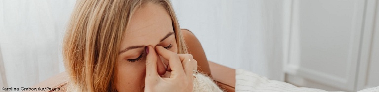 Frau fasst sich aufgrund einer allergischen Reaktion an die Nase