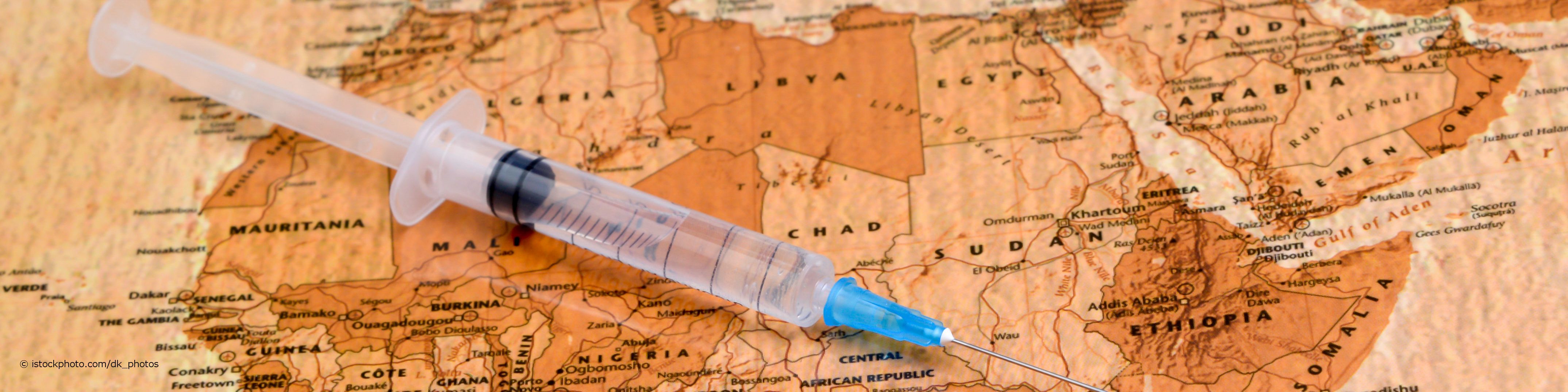 Spritze liegt als Zeichen für durchzuführende Reiseimpfungen auf einer Landkarte von Afrika.