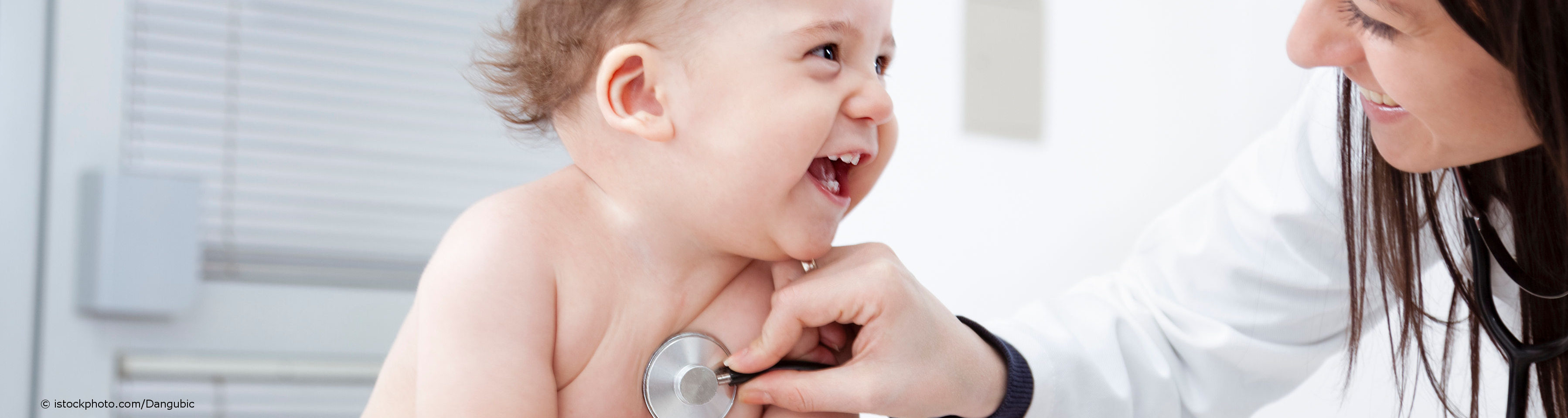 Fröhliches Baby wird von Kinderärztin mit Stethoskop abgehört.