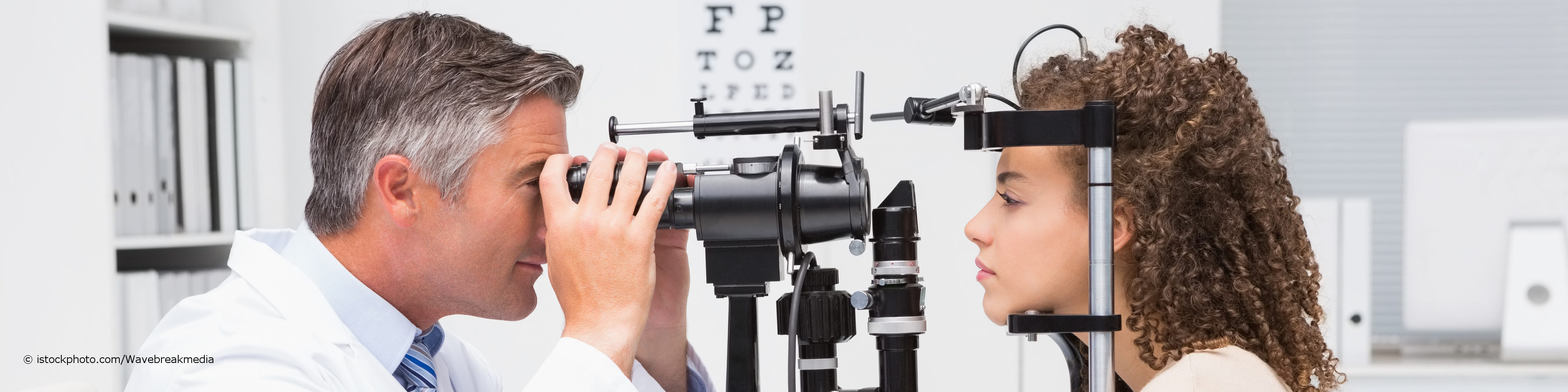 Ein Augenarzt untersucht die Augen einer Patientin an der Spaltlampe auf Erkrankungen, Sehschwächen und Fehlsichtigkeiten