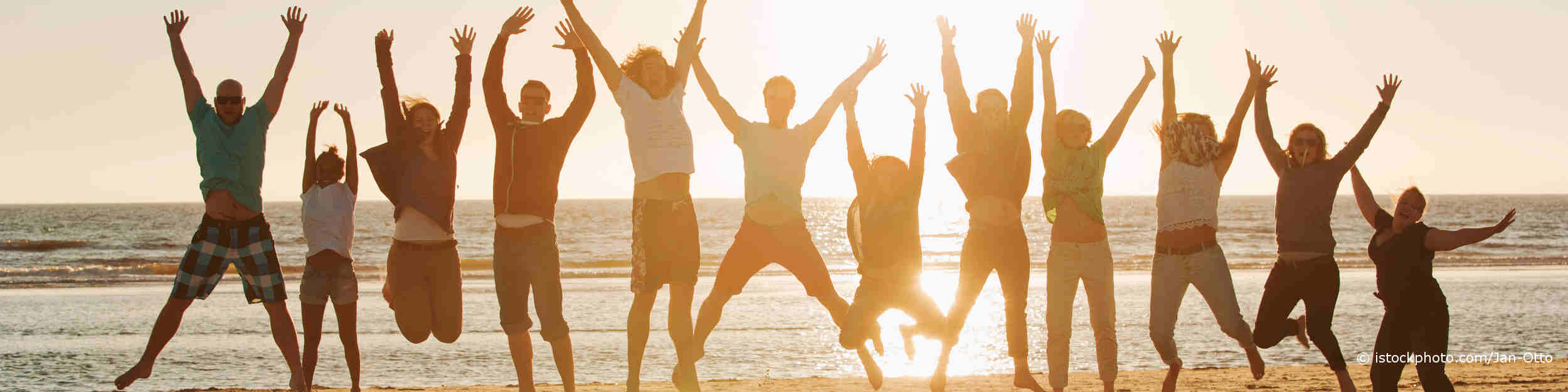 Junge Leute haben auf DocInsider die Tipps zur Stärkung des Immunsystems gelesen und hüpfen im Sonnenuntergang auf dem Sand am Meer.